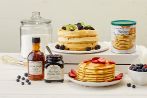 pancake stacks with berries, syrups, and sugar displayed