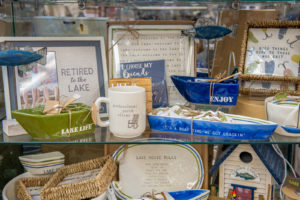 lake themed housewares display with pictures, decorative shelf boats, mugs, and more